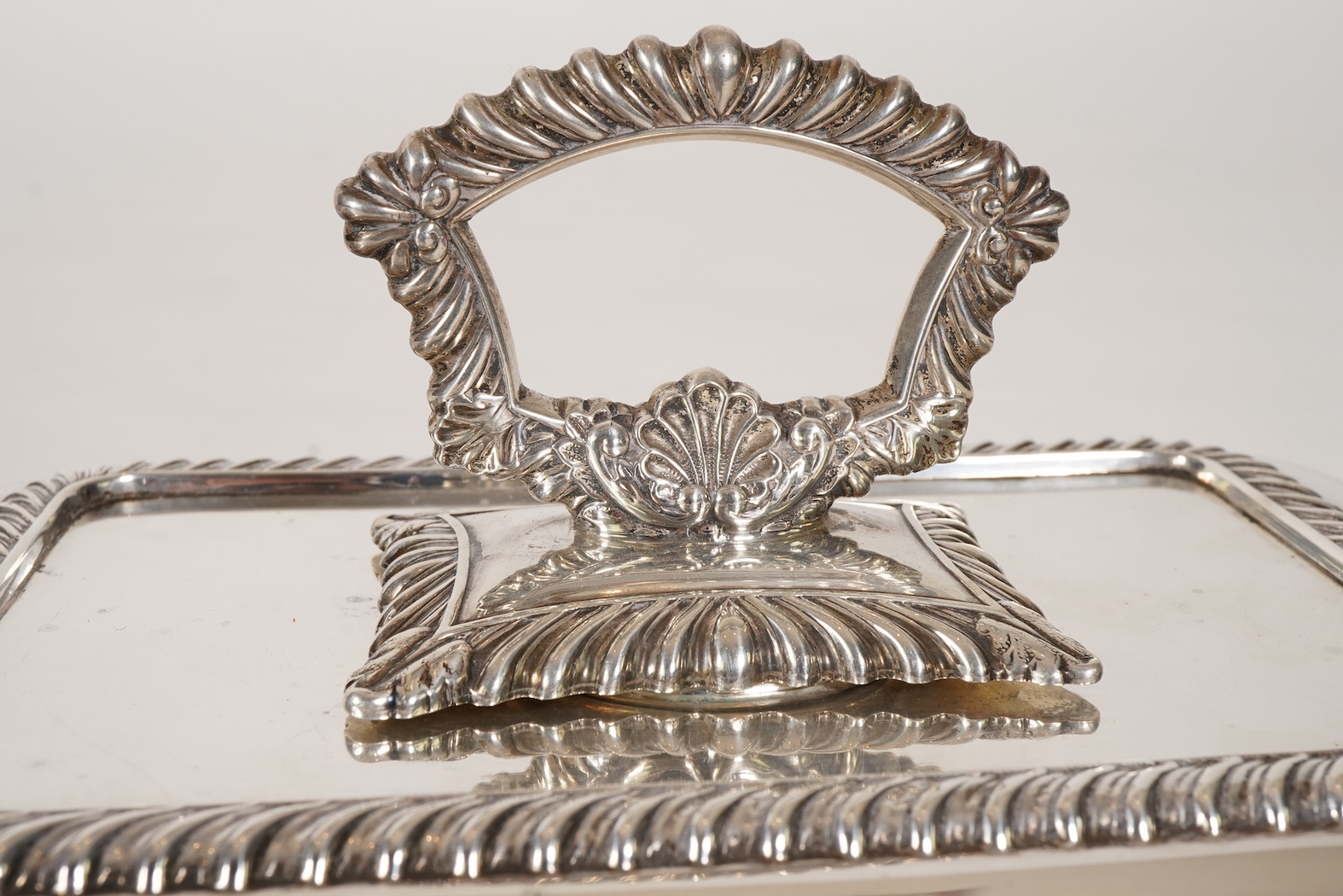A matched pair of George V silver rectangular entrée dishes and covers, both with gadrooned borders and similar unmarked handles, Ellis & Co, Birmingham, 1923 and Ellis & Co, Birmingham, 1932, base 27.8cm, 108.3oz, exclu